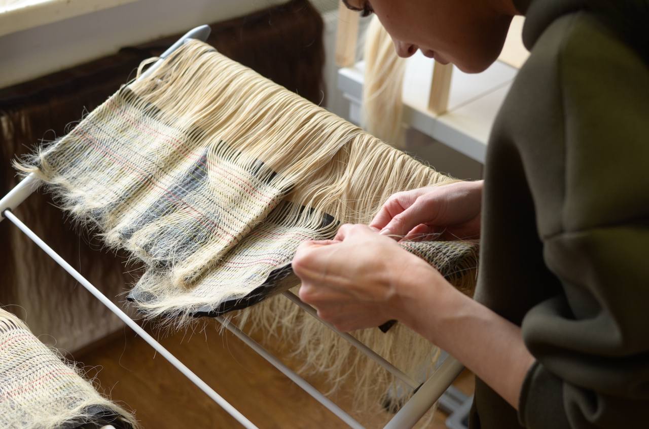 Quality control — technician examining hair extensions at the workbench